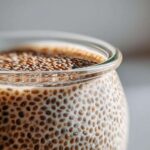 Macro shot showing the gelatinous texture of prepared Chia Pudding with visible chia seeds soaking in milk.