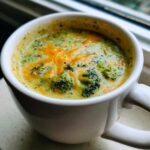 Close-up of creamy Broccoli and Cheddar Soup topped with melted orange cheddar cheese.