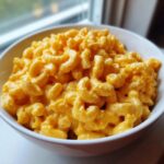 Close-up of creamy, bright orange Copycat Chick-fil-A Mac and Cheese served in a white bowl.