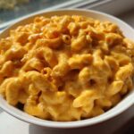 A close-up of creamy, cheesy Copycat Chick-fil-A Mac and Cheese topped with a sprinkle of paprika in a white bowl.