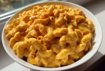 A close-up of creamy, cheesy Copycat Chick-fil-A Mac and Cheese topped with a sprinkle of paprika in a white bowl.