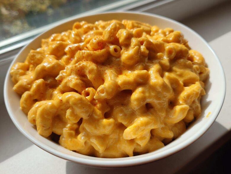 A close-up of creamy, cheesy Copycat Chick-fil-A Mac and Cheese topped with a sprinkle of paprika in a white bowl.