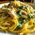 Close-up of creamy Lemon Chicken Pasta tossed with wilted spinach and seasoned with black pepper.