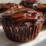 Close-up of a moist Espresso Brownie Cupcakes topped with thick, glossy chocolate ganache dripping down the side.