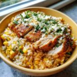 Close-up of a yellow bowl filled with the Flavor: Street Corn Chicken Rice Bowl, topped with sliced seasoned chicken and cotija cheese.