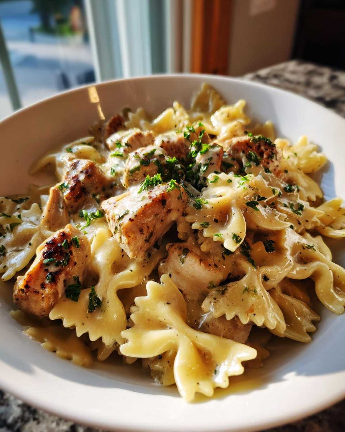A close-up of Garlic Butter Chicken Bowtie Pasta featuring bowtie noodles, seared chicken pieces, and a creamy sauce, garnished with parsley.