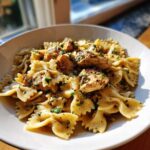 A close-up of Garlic Butter Chicken Bowtie Pasta served in a white bowl, topped with herbs.