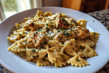 A close-up of Garlic Butter Chicken Bowtie Pasta served in a creamy sauce, topped with herbs and Parmesan cheese.