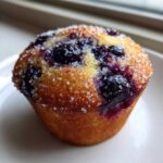 Close-up of a perfectly baked Greek Yogurt Blueberry Muffin topped with coarse sugar crystals.