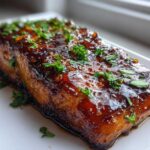 Close-up of a perfectly cooked Honey Garlic Salmon fillet covered in a thick, glossy glaze and sprinkled with fresh parsley.