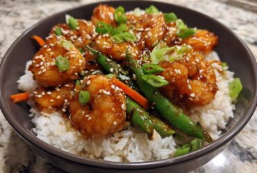 Close-up of a Honey Garlic Shrimp Bowls serving with glazed shrimp, white rice, green beans, and sesame seeds.