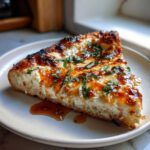 Close-up of a thick slice of Irresistible Hot Honey Ricotta Pizza topped with sweet glaze and fresh basil.