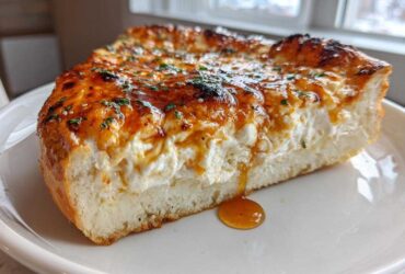 Cross-section of a thick crust pizza slice topped generously with creamy ricotta, drizzled with hot honey, making the Irresistible Hot Honey Ricotta Pizza Delight.