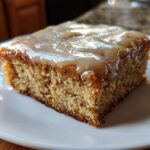 A close-up of one square of Moist Banana Bars with Browned Butter Vanilla Glaze on a white plate.