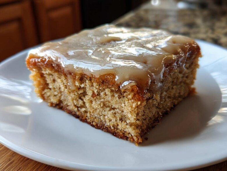 A close-up of one square of Moist Banana Bars with Browned Butter Vanilla Glaze on a white plate.