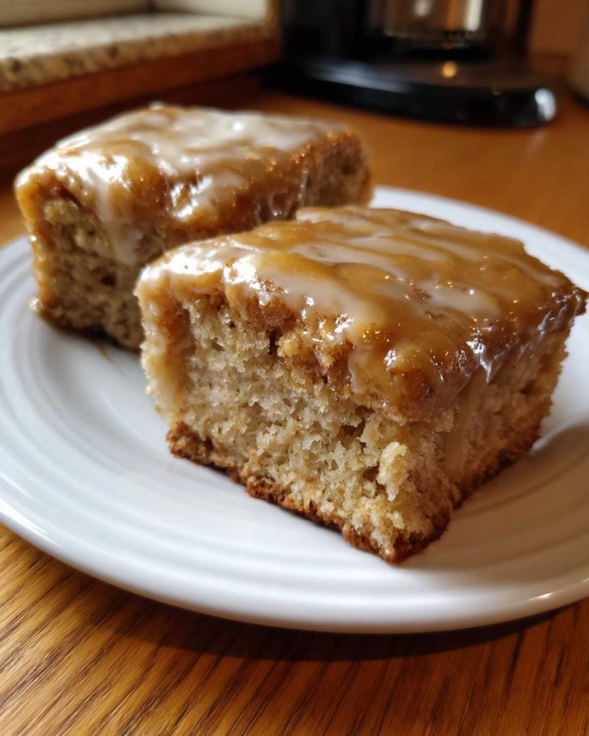 Two squares of Moist Banana Bars with Browned Butter Vanilla Glaze served on a white plate.