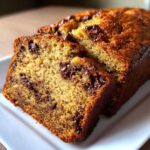Close-up of two thick slices of moist Chocolate Chip Banana Bread showing melted chocolate chips throughout the golden crumb.