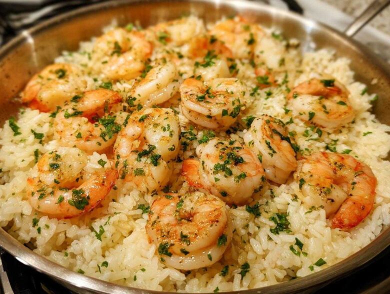 Close-up of One-Pan Garlic Shrimp and Rice garnished with parsley in a stainless steel skillet.