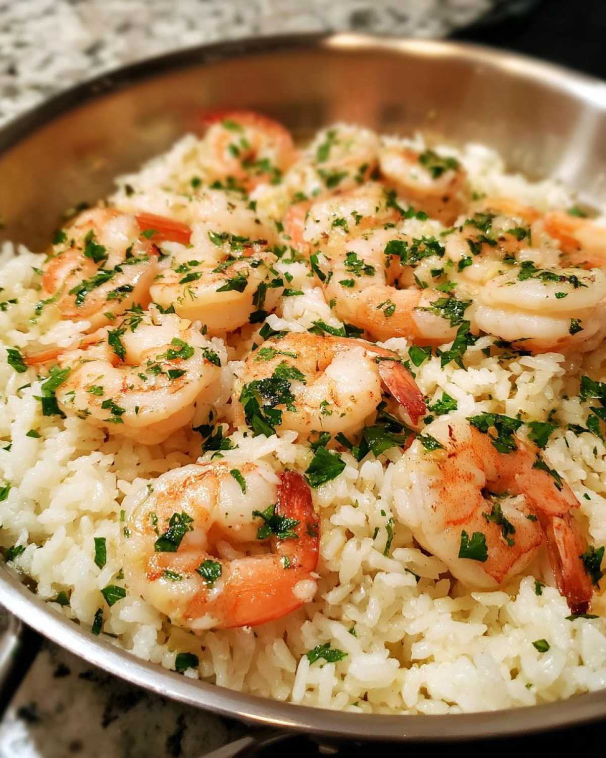 Close-up of juicy shrimp served over white rice, garnished with fresh parsley, from the One-Pan Garlic Shrimp and Rice recipe.