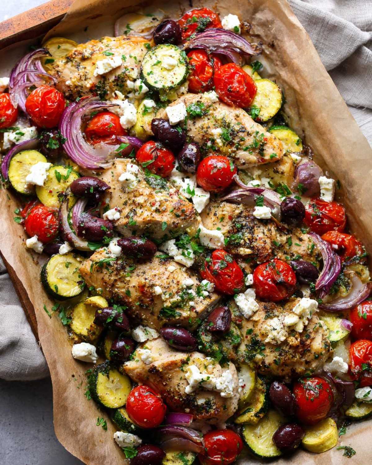 Overhead view of One-Pan Mediterranean Chicken Zucchini Bake with roasted tomatoes, olives, and feta.