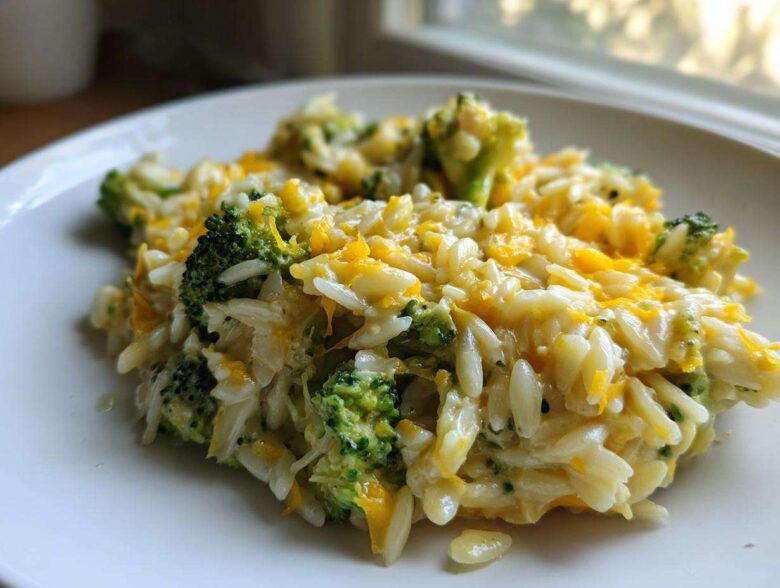 Close-up of a creamy serving of One Pot Broccoli Cheese Orzo topped with melted cheddar cheese.