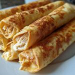 A close-up stack of golden brown Oven Rolled Chicken Taquitos showing the shredded chicken filling.