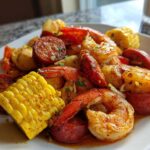 Close-up of a Quick Cajun Garlic Seafood Boil featuring shrimp, smoked sausage, corn on the cob, and potatoes.