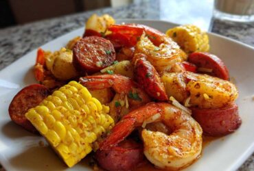 Close-up of a Quick Cajun Garlic Seafood Boil featuring shrimp, smoked sausage, corn on the cob, and potatoes.