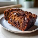 Close-up of moist slices of Quick Fudgy Chocolate Banana Bread packed with melted chocolate chips on a white plate.