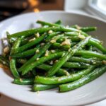 Close-up of bright green Roasted Garlic Green Beans seasoned with minced garlic served in a white bowl.