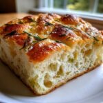 Close-up of a thick slice of Rosemary Sea Salt Focaccia showing its airy, open crumb structure and golden-brown crust.
