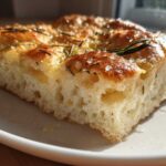 A close-up cross-section of fluffy Rosemary Sea Salt Focaccia showing its airy crumb structure and golden, salty top.