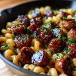 Close-up of glazed sausage meatballs mixed with pasta in a skillet, featuring the Sticky Honey Garlic Sausage Pasta Skillet.
