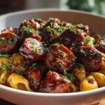Close-up of Sticky Honey Garlic Sausage Pasta Skillet featuring glazed sausage pieces and shell pasta, garnished with parsley.