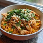 Close-up of a bowl of Street Corn Chicken Rice Bowl with shredded chicken, corn, cheese, and fresh cilantro.